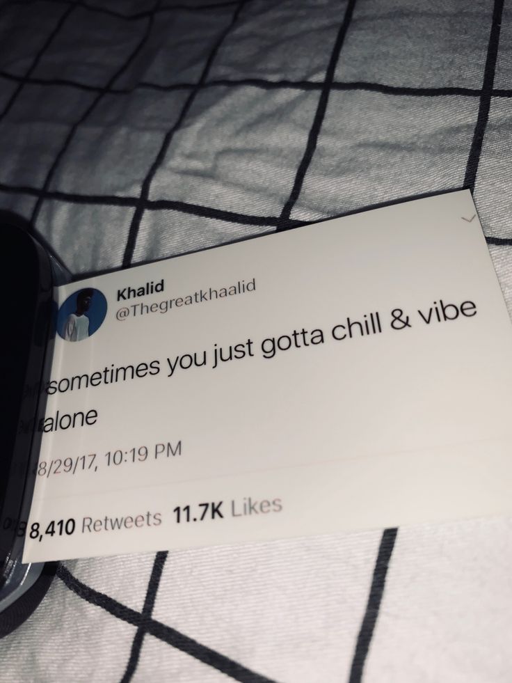 a cell phone sitting on top of a bed next to a sign that reads sometimes you just got a chill and vibe