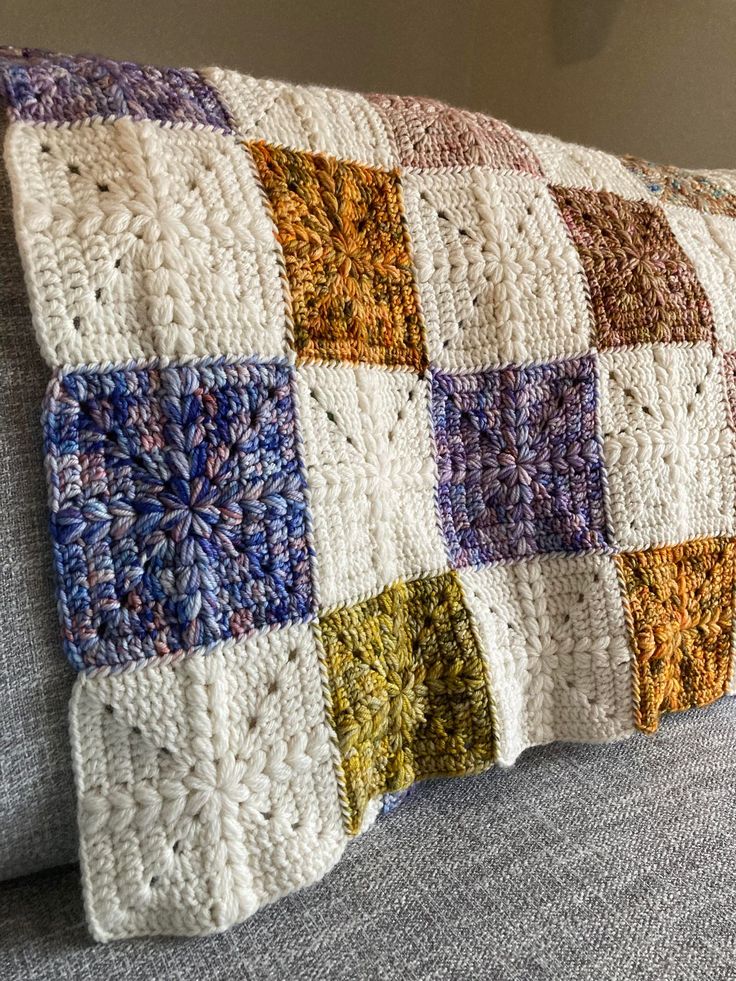 a crocheted pillow is sitting on a couch