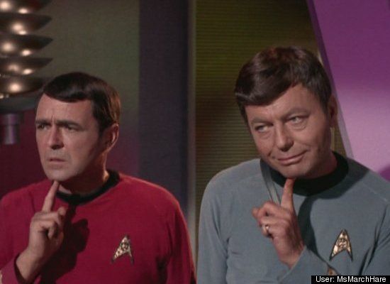 two men in star trek uniforms standing next to each other and pointing at the camera