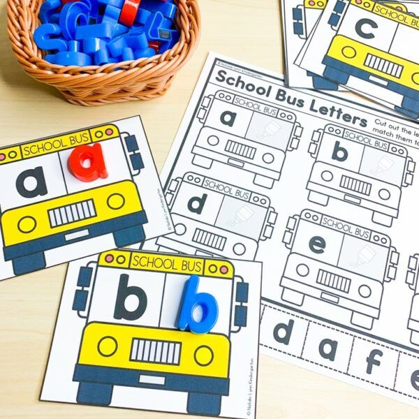 three yellow and blue bus themed alphabets are sitting on a table next to a basket full of letters