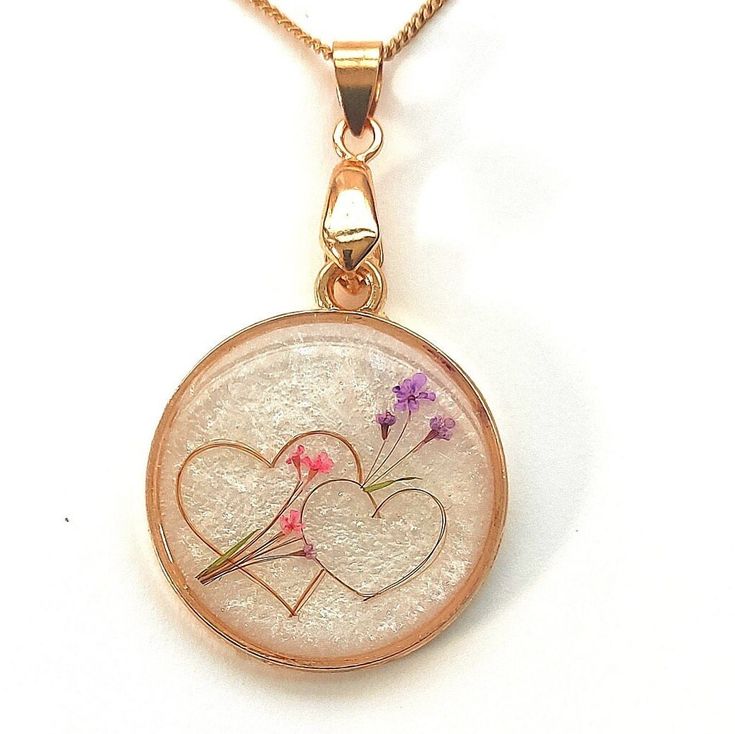 a pendant with two birds and flowers on it