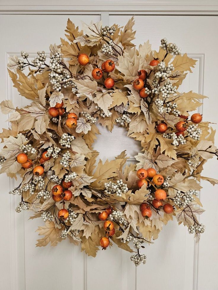 a wreath with oranges and berries hanging on the front door to give it an autumn feel