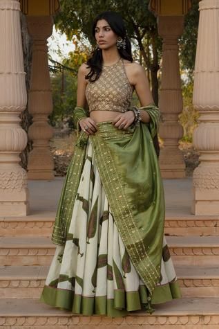 a woman in a green and white lehenga standing on steps with her hands on her hips