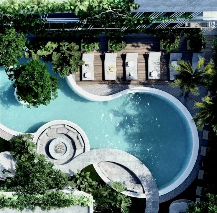 an aerial view of a swimming pool with lounge chairs and trees in the foreground