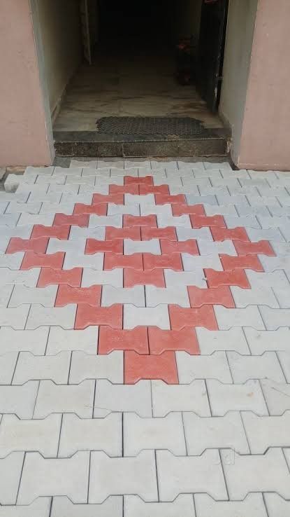 a red and white pattern on the ground in front of a building with an open door