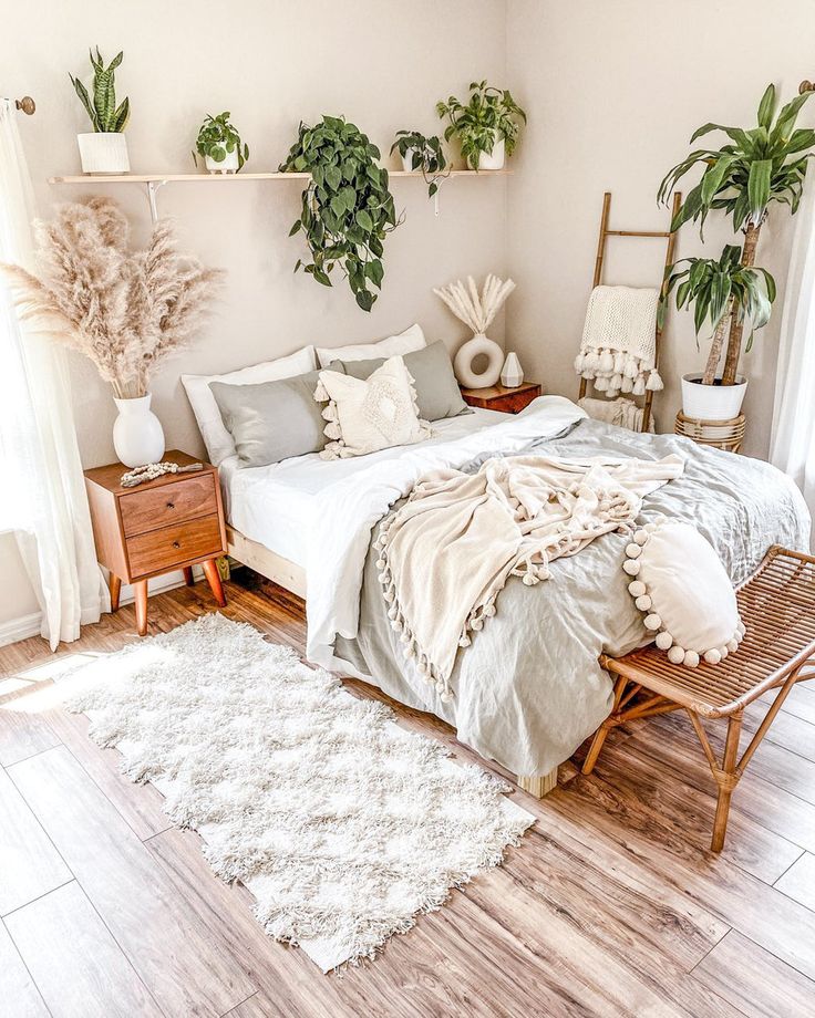 a bed sitting in a bedroom next to two potted plants