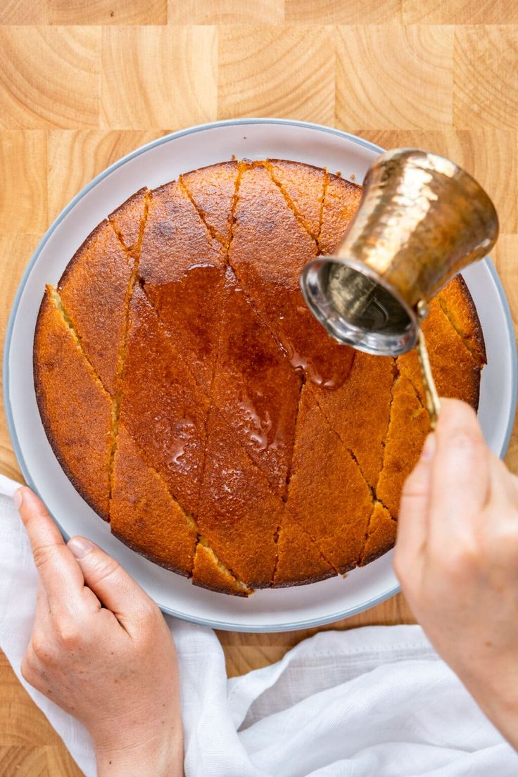 a person pouring sauce on top of a cake