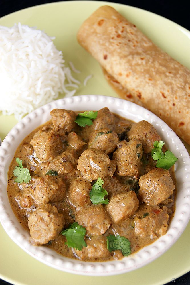 a white plate topped with meat and rice next to a pita bread on top of a table