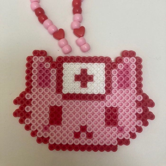 a necklace made out of legos and beads with a pink cat on the front