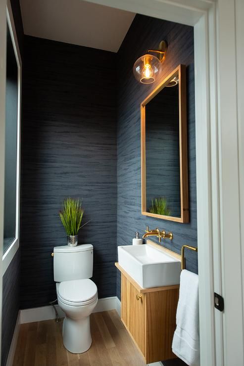 a white toilet sitting next to a sink in a bathroom under a mirror and light