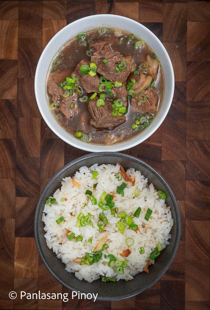 two bowls filled with rice and meat next to each other on a wooden table top