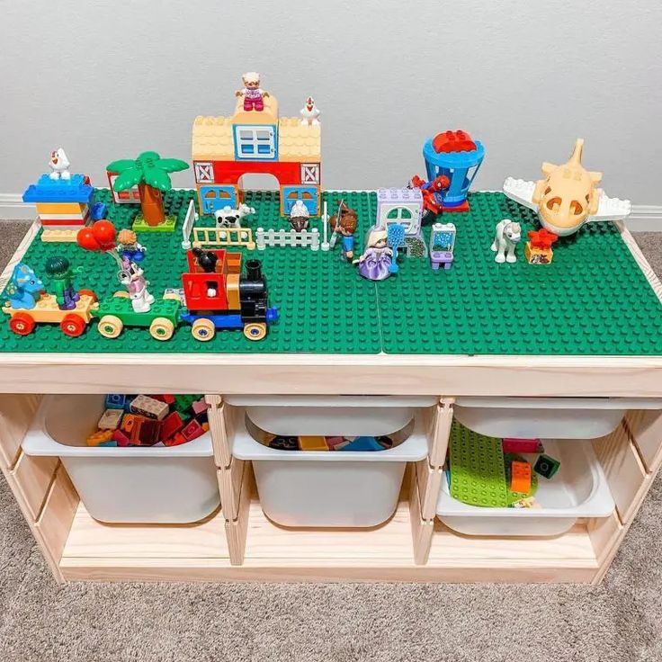 a toy table with legos on it and toys in bins underneath the table