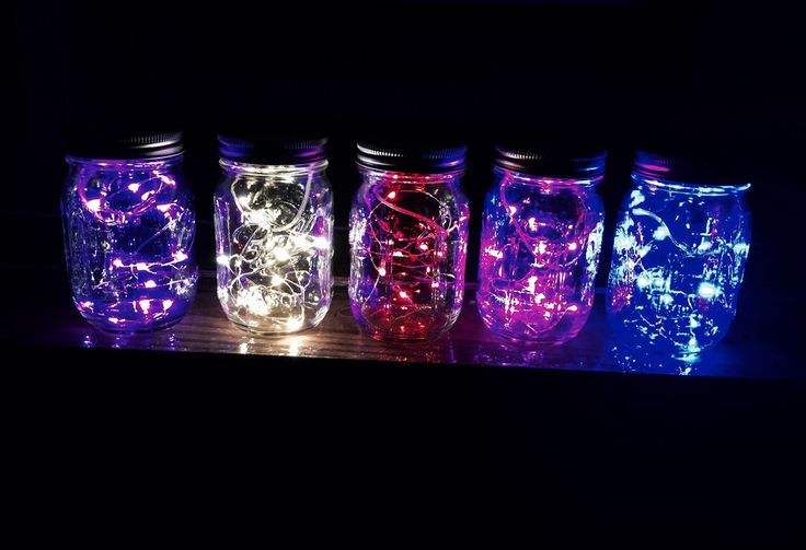 there are many mason jars with lights in them