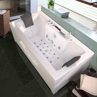 a white bath tub sitting on top of a black tiled floor next to a window