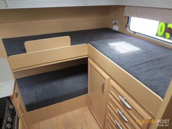 the inside of a camper with wood cabinets and black carpet