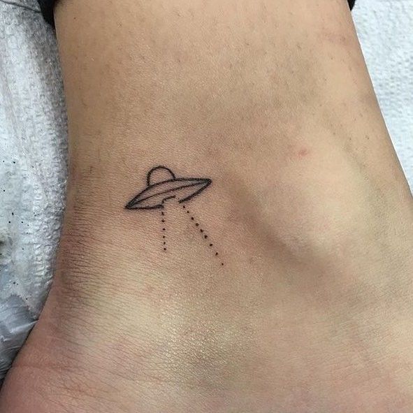 a small saturn tattoo on the side of a woman's stomach, with an airplane flying through it