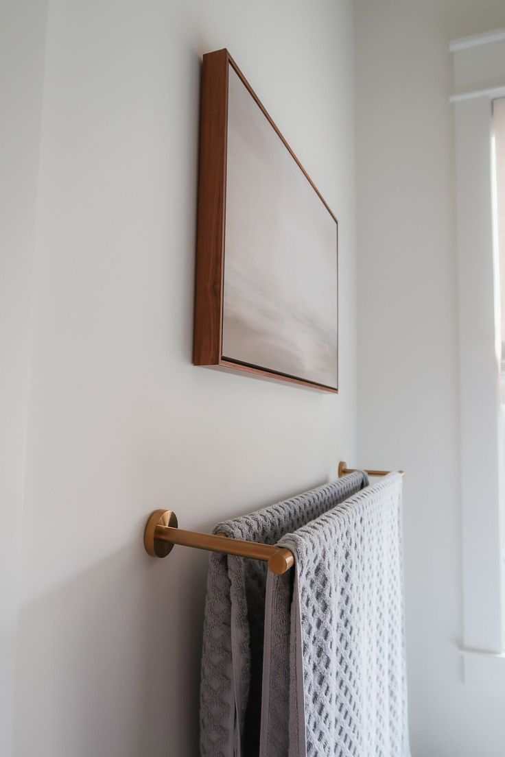 a towel rack is hanging on the wall next to a window with a mirror above it