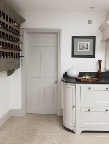 a kitchen with white cabinets and black counter tops next to a wine rack on the wall