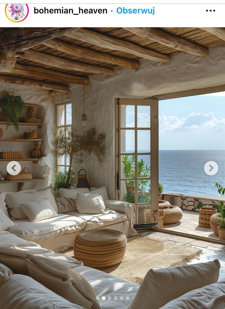 a living room filled with furniture next to an open window overlooking the ocean and beach