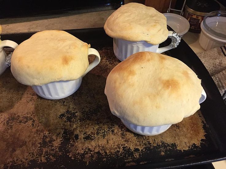 three baked breads sitting on top of a baking sheet in front of an oven