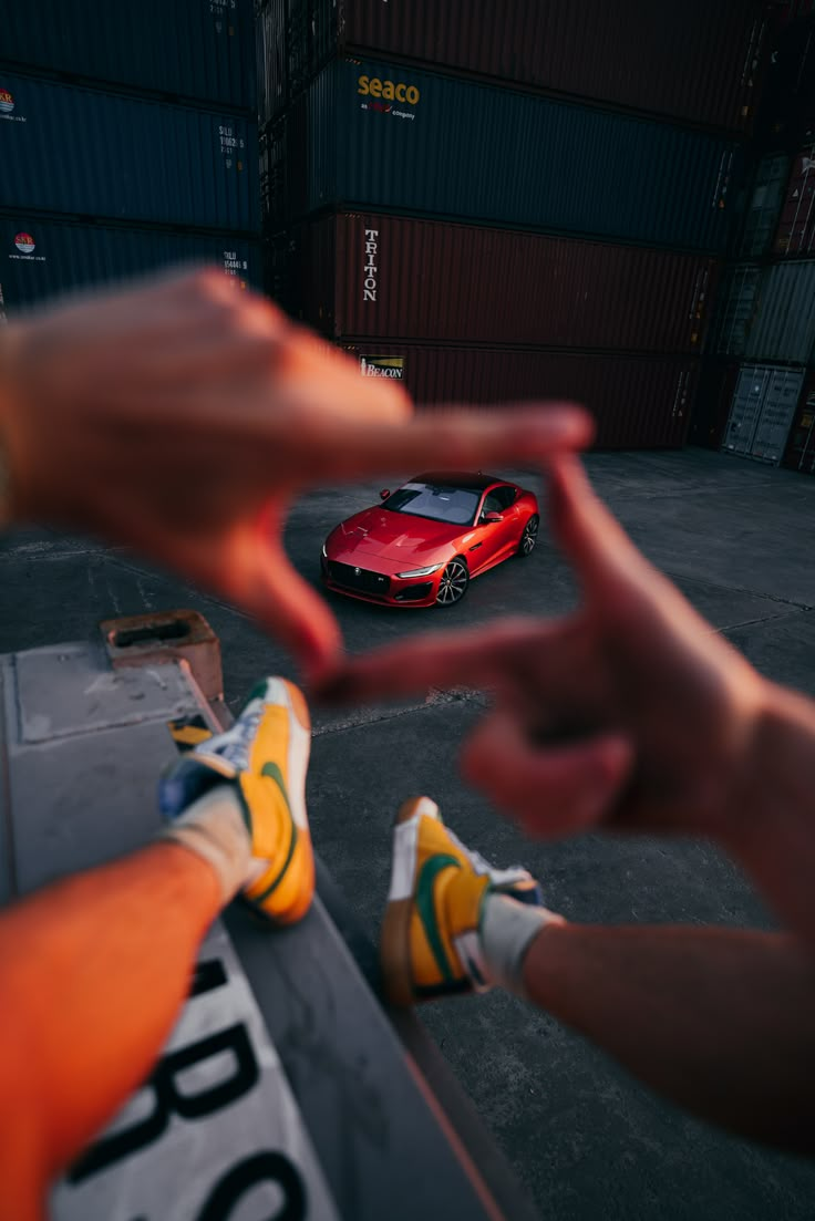 two hands reaching out towards a red sports car