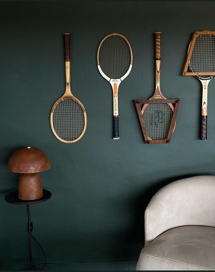 four tennis rackets are hanging on the wall next to a chair and table lamp