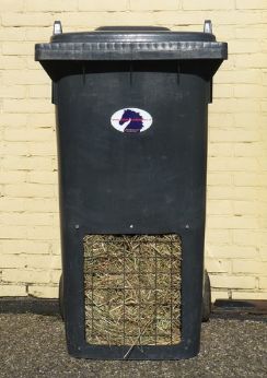 a black trash can sitting next to a brick wall with a purple and white sticker on it