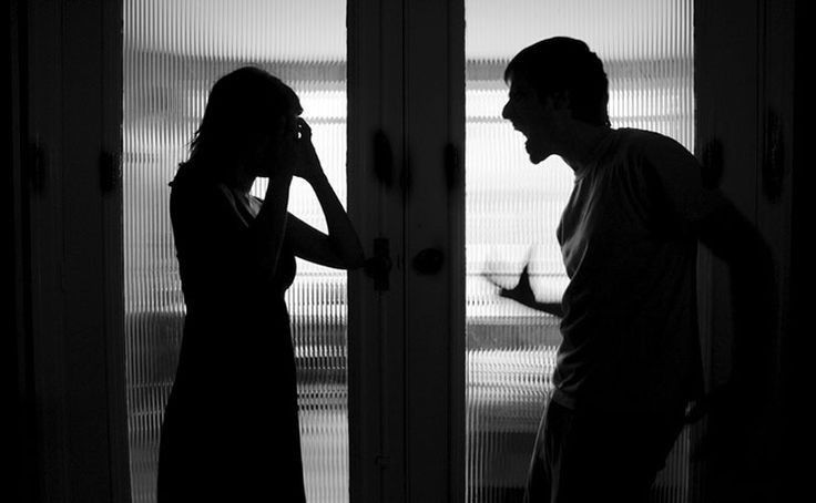 a man standing next to a woman in front of a door while talking on a cell phone