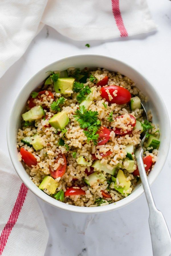 a white bowl filled with rice and veggies next to a red striped napkin