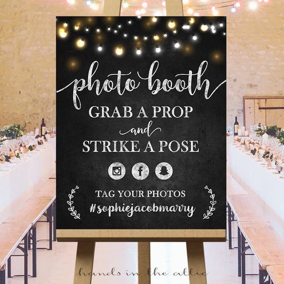 a photo booth sign with lights on the ceiling and tables set up for an event