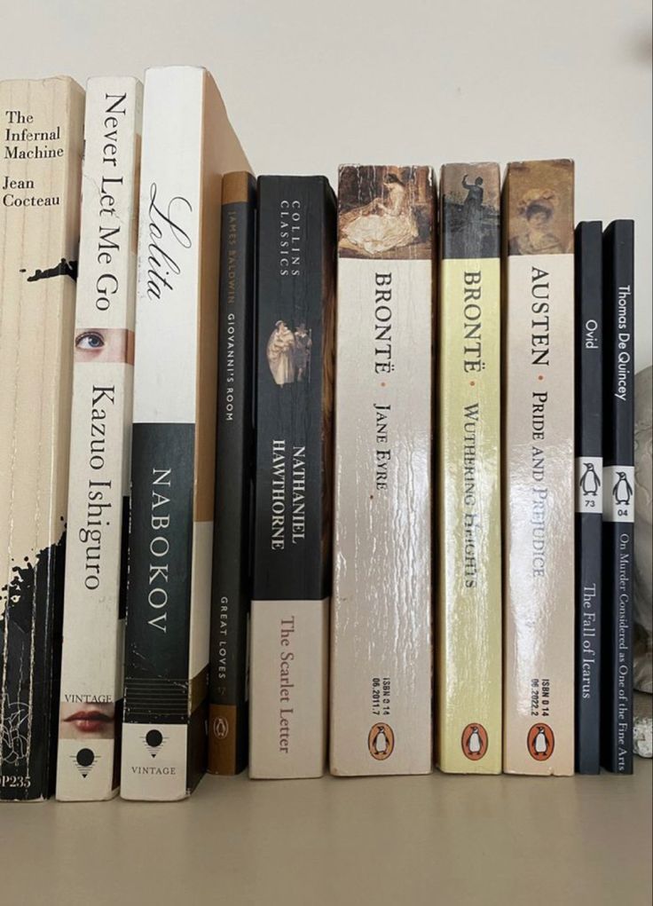 a row of books sitting on top of a wooden shelf next to a white statue