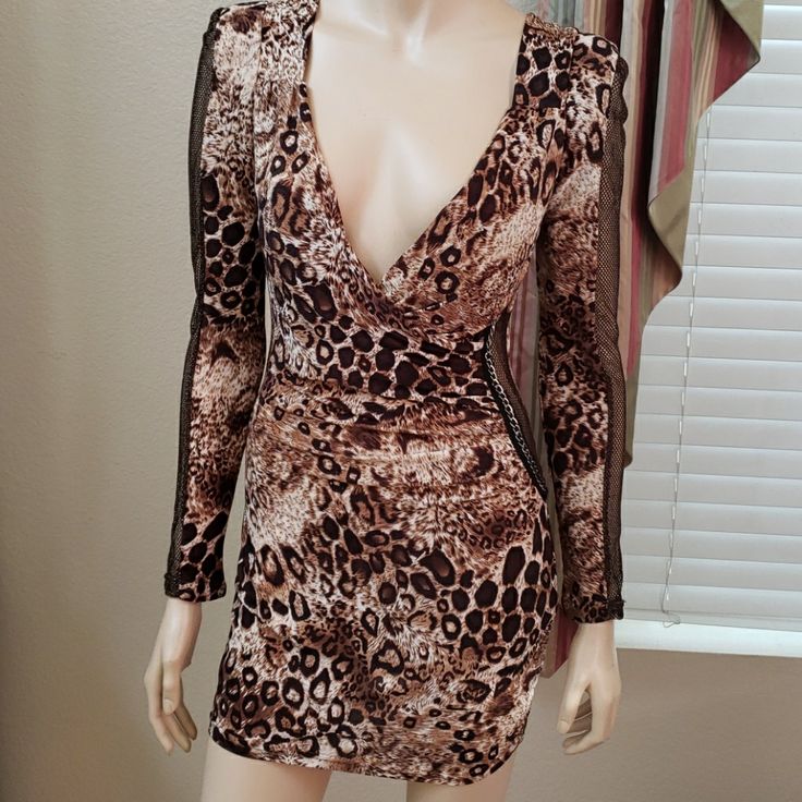 a mannequin wearing a leopard print dress with long sleeves and an open back