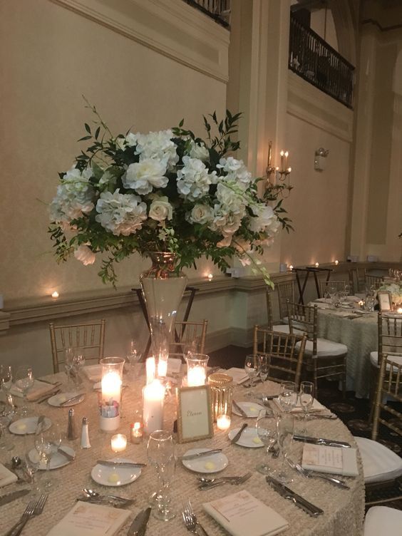 the centerpieces on this table are filled with white flowers and lit candles for an elegant touch