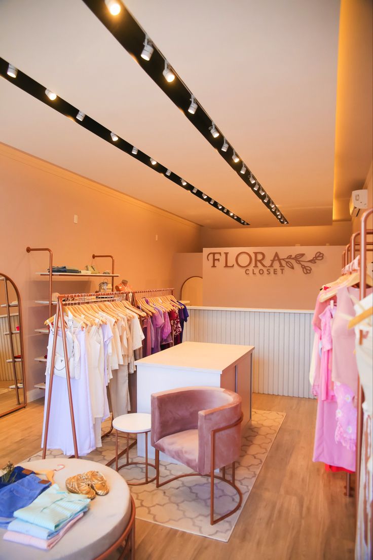 the interior of a clothing store with clothes on hangers and tables in front of them