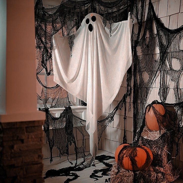 two pumpkins sitting in front of a white curtain with black net hanging from it