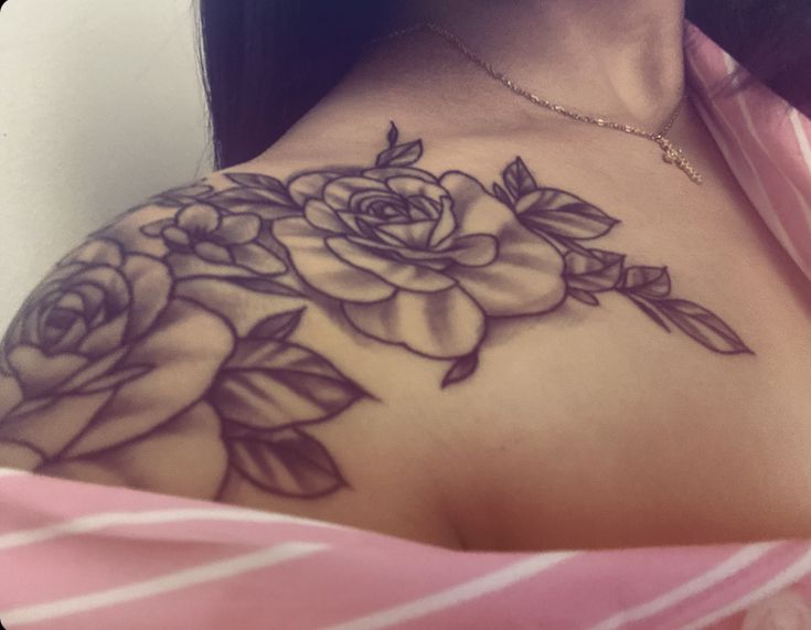 a woman with a rose tattoo on her shoulder and chest is looking at the camera