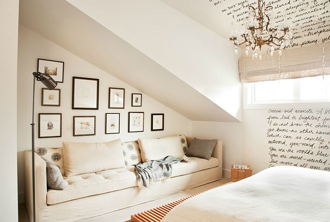 a bed sitting under a window next to a white couch in a room with pictures on the wall