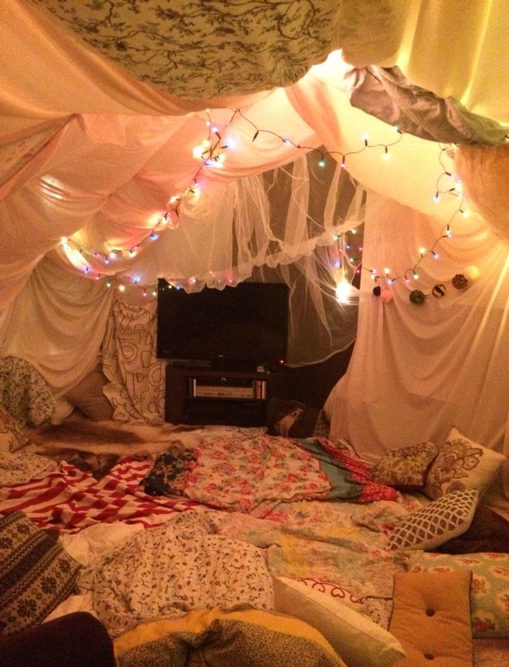 an unmade bed with lots of lights on the ceiling and curtains over it's head