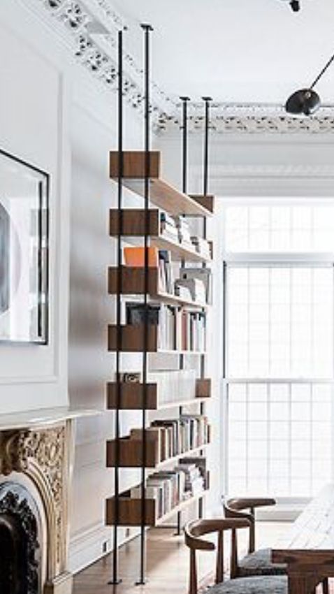 a living room filled with furniture and a fire place in front of a book shelf