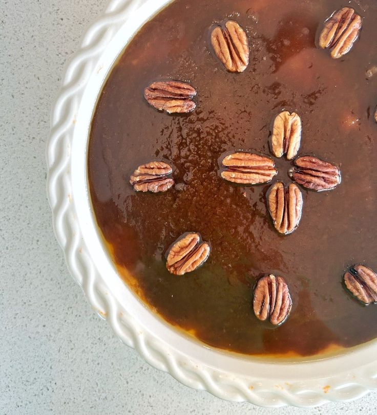 a bowl filled with caramel and pecans on top of a table