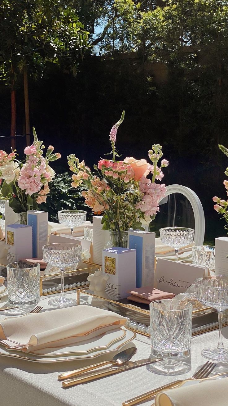 a table set with place settings and flowers in vases