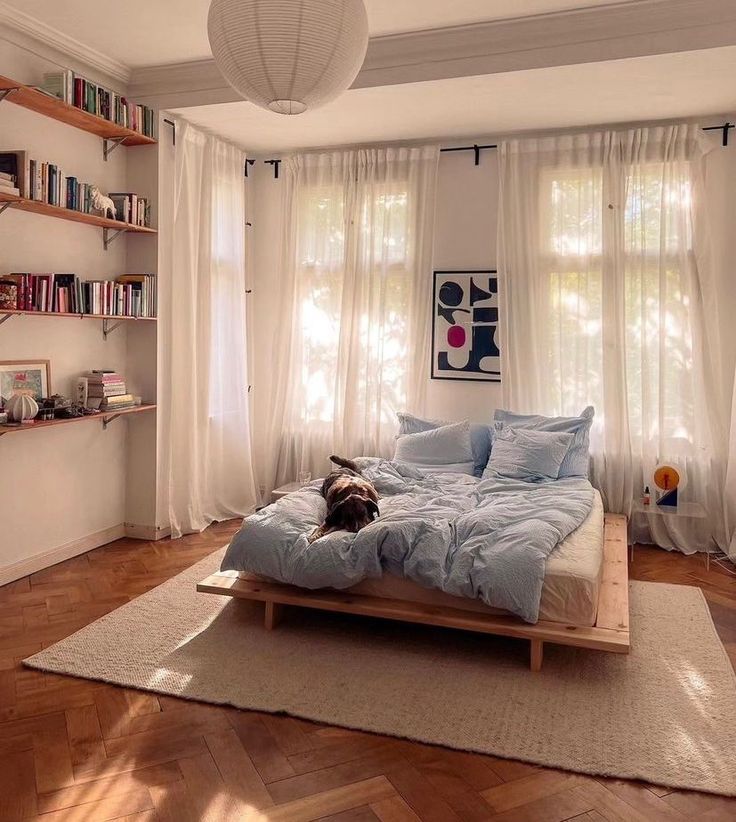 a bed sitting on top of a wooden floor in a bedroom next to a window