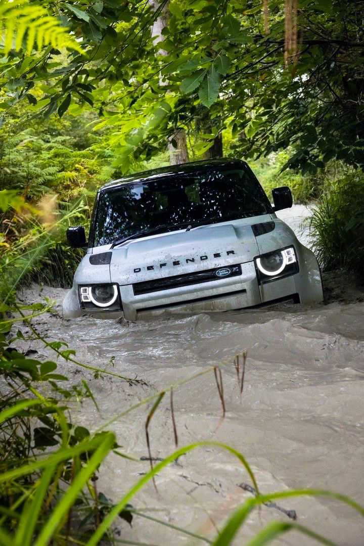 a car is driving through some water in the woods