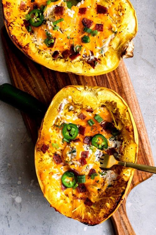 two stuffed bell peppers on a cutting board with cheese and green onions in the middle