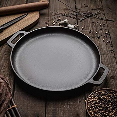 an iron skillet sitting on top of a wooden table next to other cooking utensils