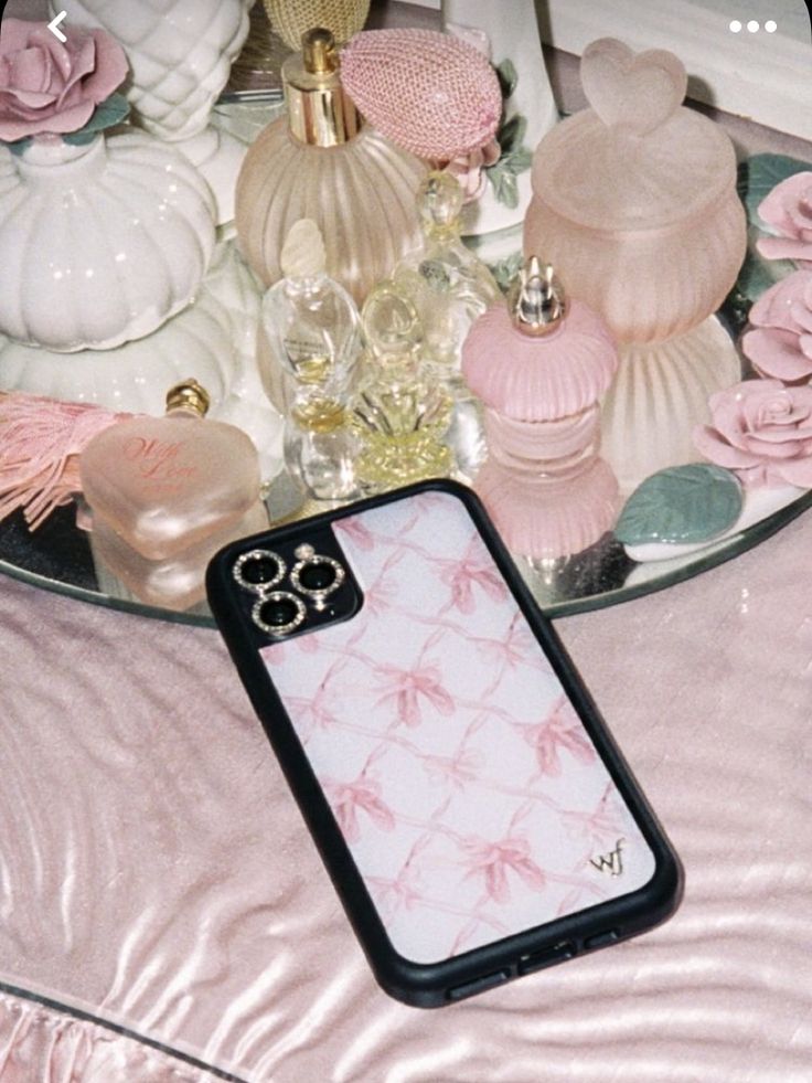 a cell phone case sitting on top of a table covered in pink flowers and candles