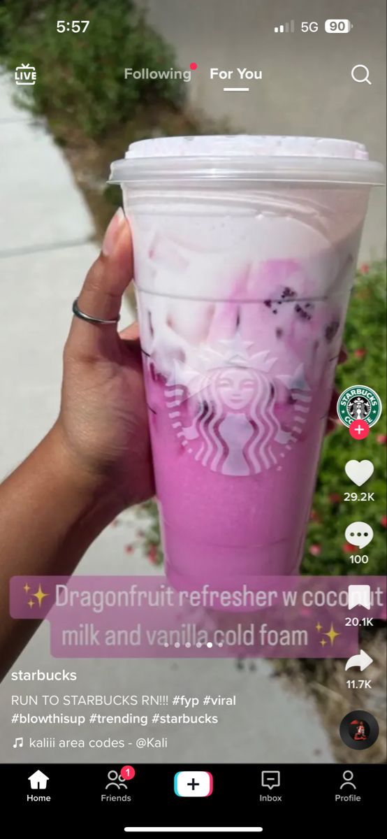 a hand holding up a pink starbucks cup with white designs on the lid and bottom