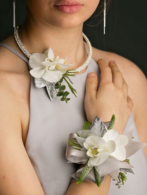 a woman in grey dress with flowers on her arm and necklace attached to her neck