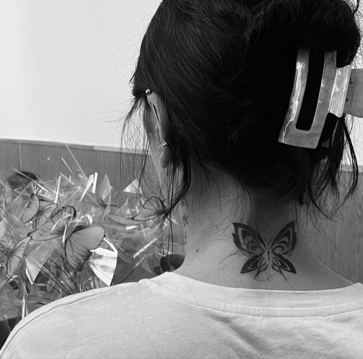 a woman with a butterfly tattoo on her neck