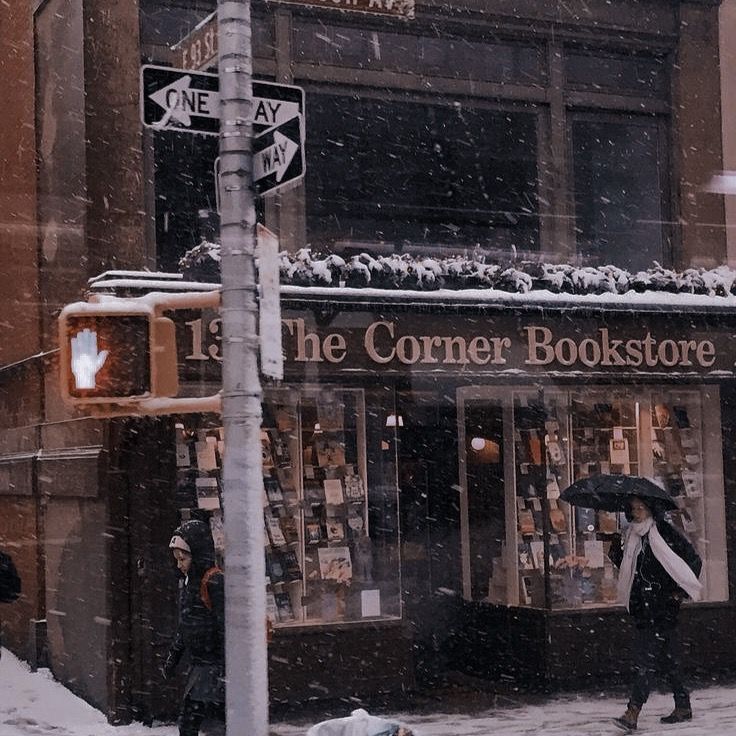 the corner bookstore is covered in snow as people walk past it on a snowy day